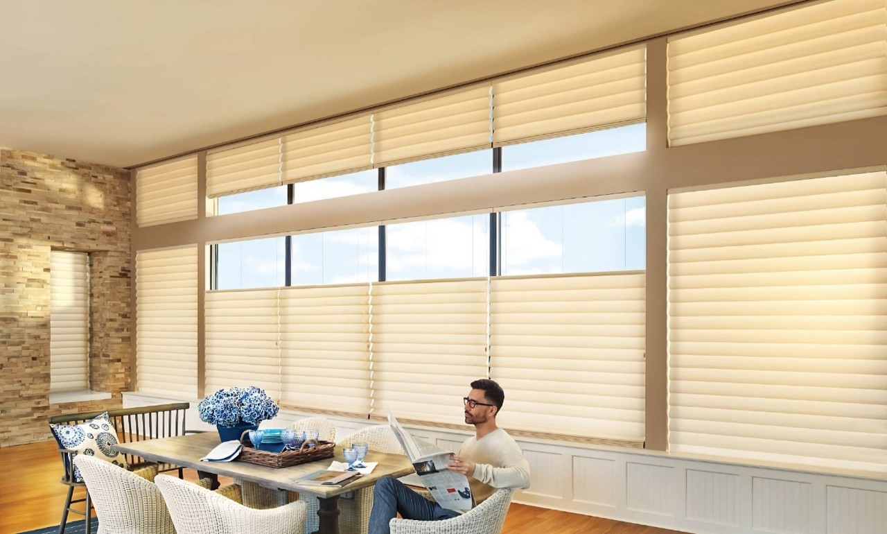 Man at a dining room table reading with Hunter Douglas Vignette® Roman Shades on the windows at All About Blinds near Johnson City, TN