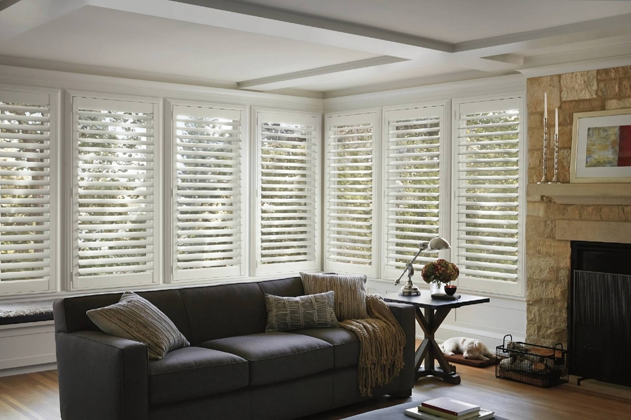 White Hunter Douglas NewStyle® Composite Shutters on large windows in a cozy living room at All About Blinds near Johnson City, TN